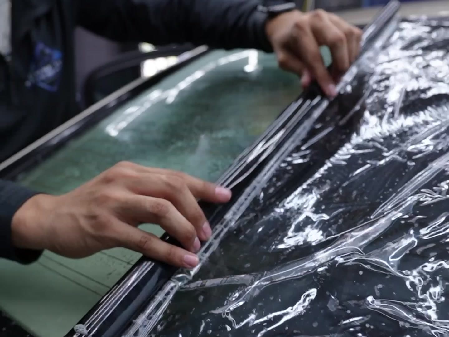 Cruise and Clean installer laying dark ceramic tint film onto a car's rear window