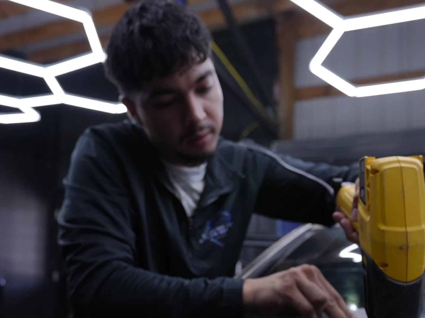 Cruise and Clean installer heat-shrinking window tint film under the studio's hex lights